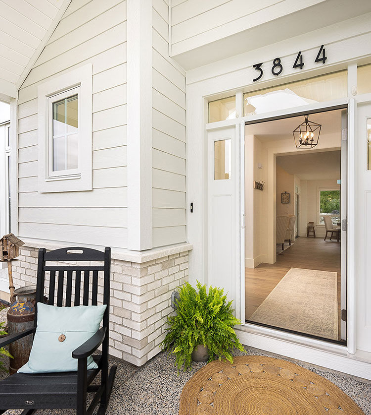 Retractable door screen on a modern home entrance with rocking chair and potted ferns