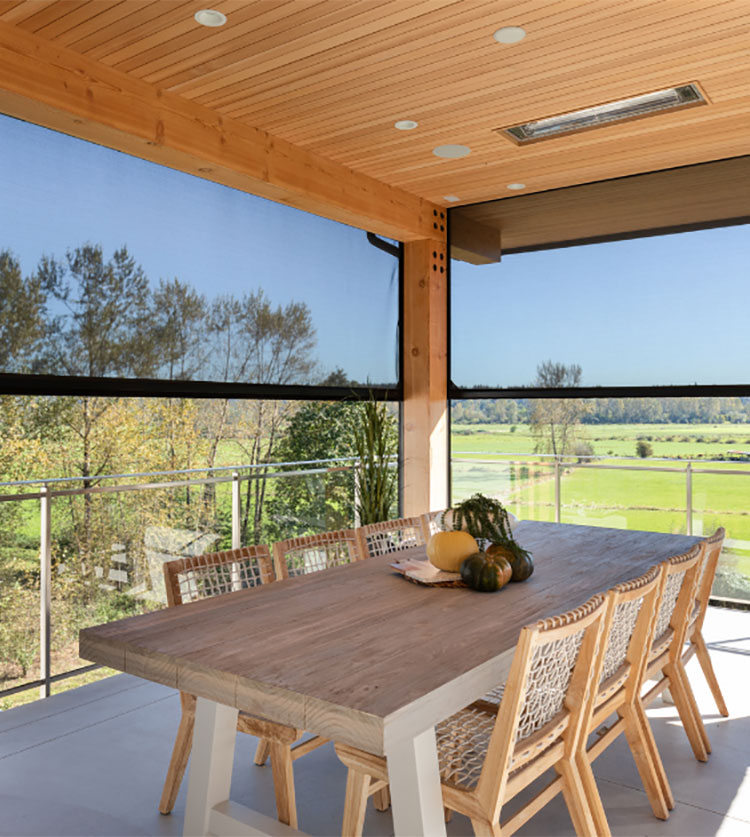 Covered patio with motorized retractable screens overlooking green fields